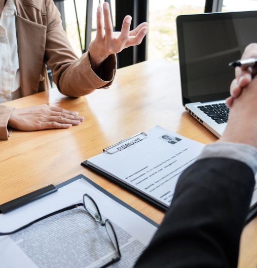 Ein Mann und eine Frau sitzen an einem Tisch mit einem Laptop und diskutieren.