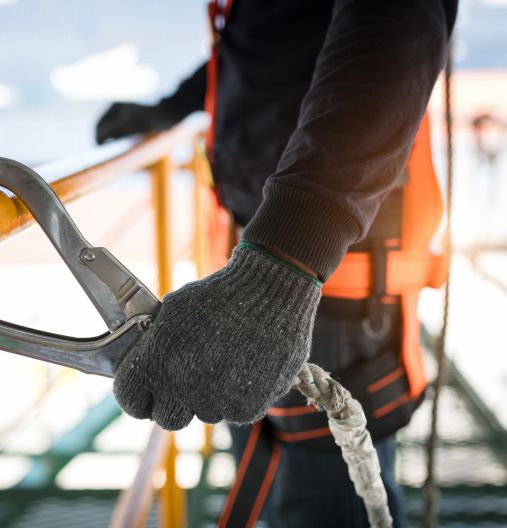 Eine Person in einer Sicherheitsweste hält ein Seil in der Hand.